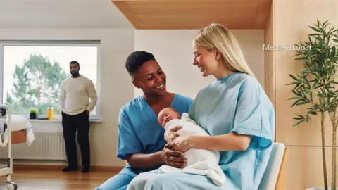 Hebamme im Gespräch mit einer Mutter und ihrem Neugeborenen im Wochenbettzimmer
