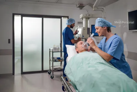 Expertin Anästhesiepflege bereitet im Einleitungsraum einen Patienten auf die Narkose vor, Anästhesist mit Haube am Narkosegerät