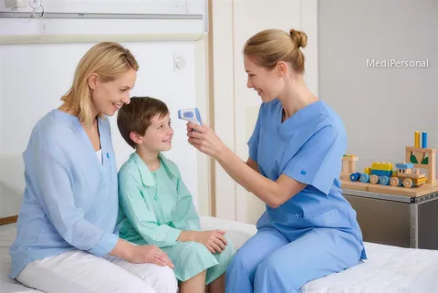 Pflegefachfrau misst auf der Kinderstation eines Spitals in Aarau bei einem Kind im Beisein der Mutter das Fieber, Spielecke im Hintergrund