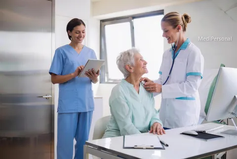 Pflegeexpertin APN untersucht im Sprechzimmer einer ambulanten Klinik in Bern eine ältere Patientin mit dem Stethoskop, Pflegefachfrau mit Tablet daneben